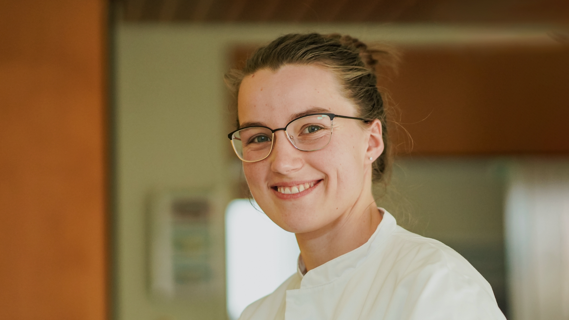 Junge Ärztin mit Brille und hochgestecktem Haar, lächelnd